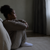 a black female adult sitting alone in a quiet room, showing depression in autistic people